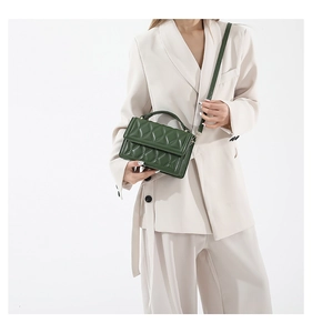 Detail of dark green quilted leather handbag with gold hardware and curved handle