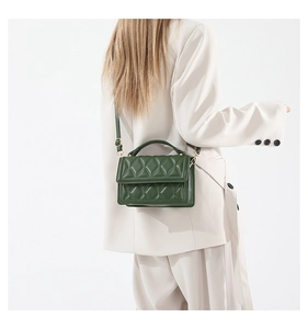 Detailed close-up of a dark green quilted handbag with gold hardware and top handle