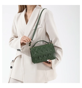 Close-up of green quilted leather bag with gold hardware worn on a beige blazer