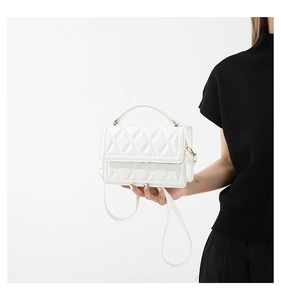 Detailed close-up of a white quilted crossbody bag with elegant stitching and leather texture