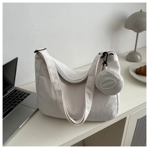 Gros plan du sac bandoulière en velours côtelé blanc avec texture et mini pochette