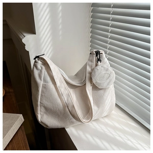 Detail of white corduroy tote bag with mini round pouch and adjustable strap under light