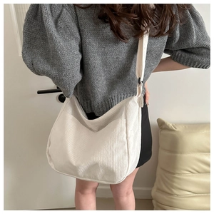Detail of cream corduroy crossbody tote bag with wide strap and textured ribbing