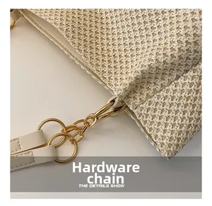Detail showing golden hardware chain and leather strap on woven straw tote bag