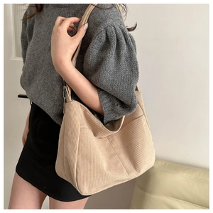 Detail of beige corduroy tote bag showing soft ribbed texture and large exterior pocket