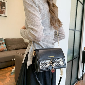 Chic black crossbody bag with tweed flap and gold chain strap worn by a model