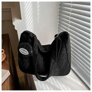 Close-up of black corduroy tote bag texture and hanging round coin purse on a sunny window
