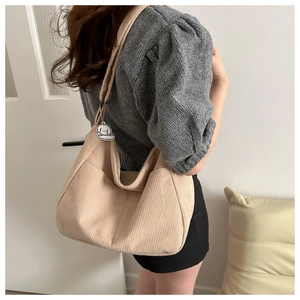 Detailed texture of beige corduroy shoulder bag featuring a cute puppy pendant decor