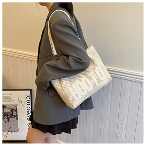 Close-up of beige knit tote bag with 3D HOOTO lettering and metal ring strap detail