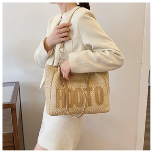 Detail of large straw tote bag with HOOTO leather patch and brown PU shoulder straps