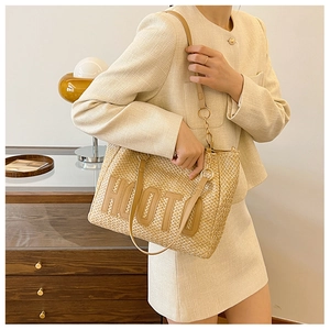 Detail of woven straw tote bag with HUOTO embroidery and leather handle on a model