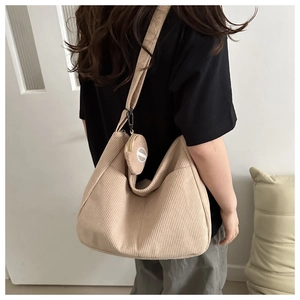 Detail of light beige corduroy tote bag featuring a matching round coin purse pendant
