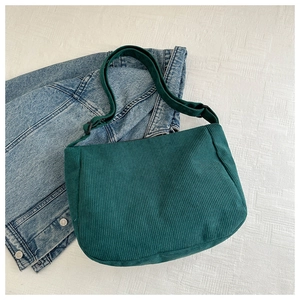 Detail of dark green corduroy shoulder bag showing fabric texture and adjustable strap