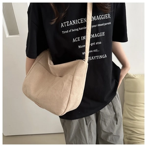Close-up of a minimalist beige corduroy crossbody tote bag worn by a model