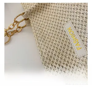 Detailed macro view of woven cream tote bag with gold chain and fashion logo patch