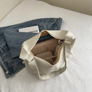 Minimalist white leather tote bag with geometric stitching shown with daily essentials