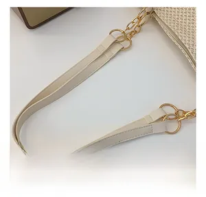 Close-up of cream leather handle with gold ring and chunky chain on woven tote bag