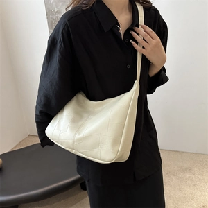 Minimalist cream white shoulder bag with geometric stitching shown on a model
