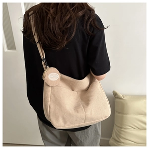 Detail of beige corduroy crossbody bag featuring a matching round mini coin purse and texture