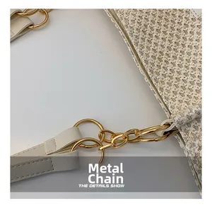 Detail of woven straw tote bag featuring white leather strap and gold hardware chain link