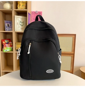 Detailansicht des wasserfesten schwarzen Nylon-Rucksacks mit Mode-Logo auf Holzregal