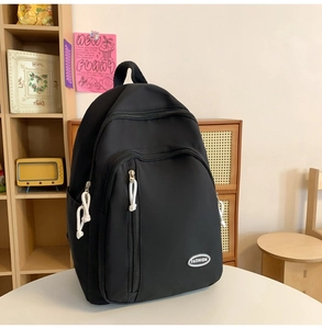 Detail des schwarzen wasserdichten Rucksacks mit Reißverschlüssen und Modepatches im gemütlichen Zimmer