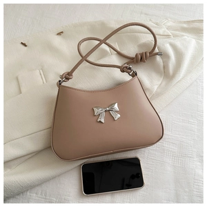 Close-up of beige hobo bag with silver bow buckle and knotted strap detail