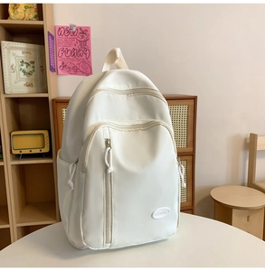 Detail eines cremeweißen wasserdichten Nylonrucksacks mit minimalistischem Gummi-Logo