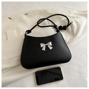 Detail of silver bow decoration and matte black leather on chic underarm handbag
