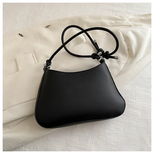 Detailed texture of black matte leather shoulder bag with silver metal buckles on fabric