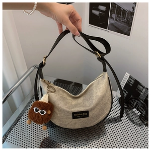 Detail of canvas crescent bag with black leather trim and a cute brown fur ball charm