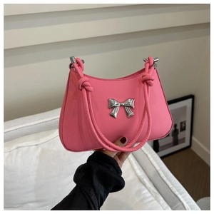Detail of a pink matte leather handbag featuring a silver bow buckle and knotted handle