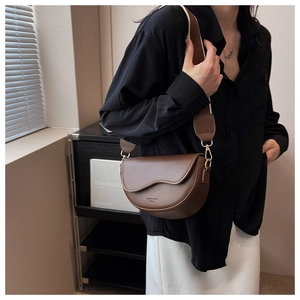 Detail showing deep brown leather saddle bag with wide woven strap and gold hardware