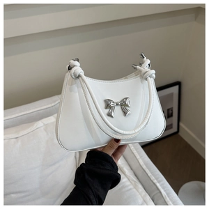 Detail of white leather underarm bag featuring a silver metal bow and knotted handle