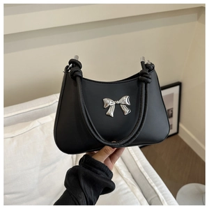 Close-up of black leather handbag with silver metal bow and knotted handle detail