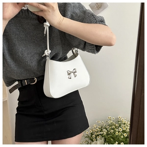 Detail of white hobo bag with silver bow buckle shown in a mirror selfie style