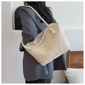 Detail of straw tote bag with floral embroidery and braided cotton rope handles