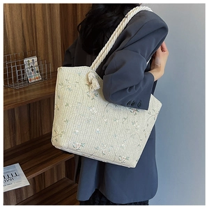 Detail of floral embroidery on a cream woven tote bag with cotton rope handles