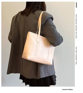 Detail of cream tote bag featuring vertical wavy texture and shoulder strap on a model