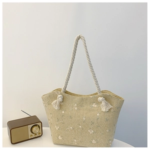 Detailed texture of straw woven tote bag featuring white floral embroidery and cotton rope