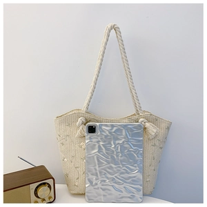 Detail of straw woven tote bag featuring delicate flower embroidery and cotton rope handles