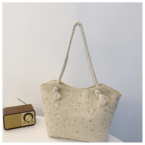 Detail of white woven tote bag with green floral embroidery and cotton rope handles