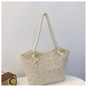 Close-up of straw tote bag featuring floral embroidery and cotton rope shoulder straps
