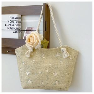 Detail of straw tote bag with white flower embroidery and rustic hemp rope handles