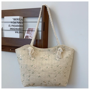 Detail of straw tote bag with floral embroidery and knotted cotton rope handle