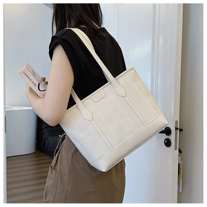 Détail d'un grand sac cabas blanc texturé porté par un mannequin à l'épaule
