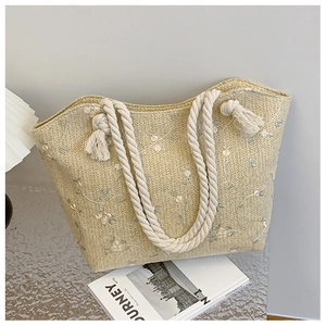 Detail of straw tote bag with floral embroidery and thick cotton rope handles for summer