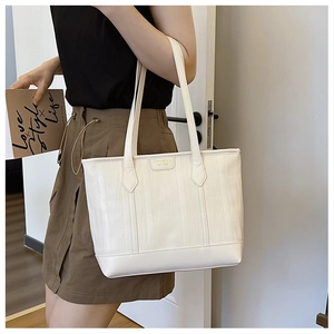 Close-up of a cream white tote bag with vertical ripple texture and small brand logo