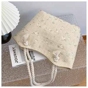 Detail of cream straw tote bag with floral patterns and thick cotton rope handles