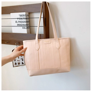 Détails de la texture à vagues et du logo métallique sur le sac cabas beige